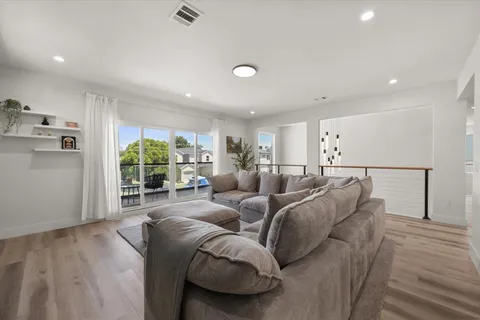a living room with furniture a large window and wooden floor