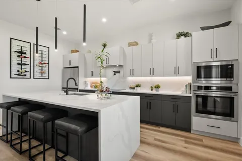 a kitchen with stainless steel appliances a stove a sink and white cabinets