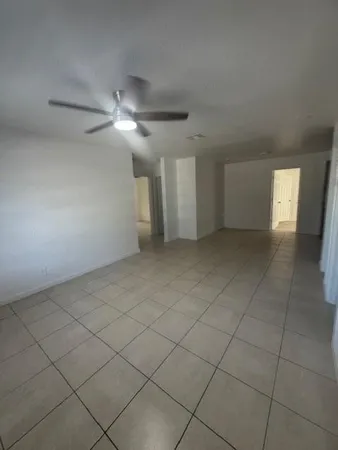 a view of an empty room and a chandelier fan