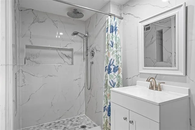 a bathroom with a sink shower and a mirror