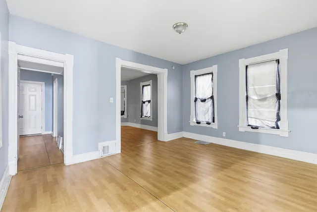 a view of an empty room with window and wooden floor