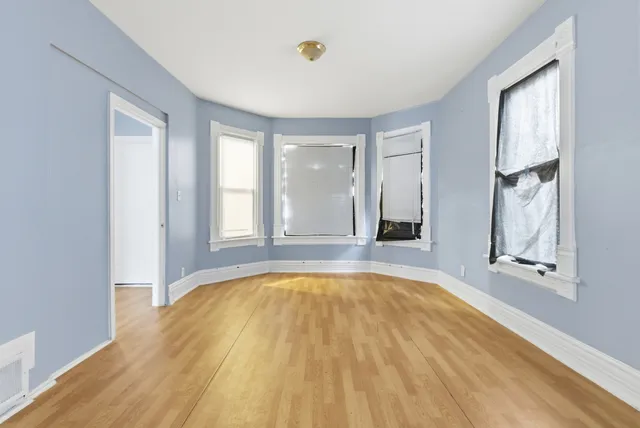 a view of a bedroom with wooden floor and windows