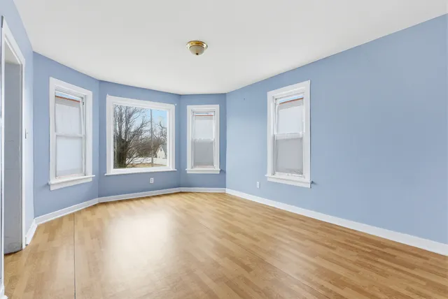 a view of an empty room with a window and wooden floor