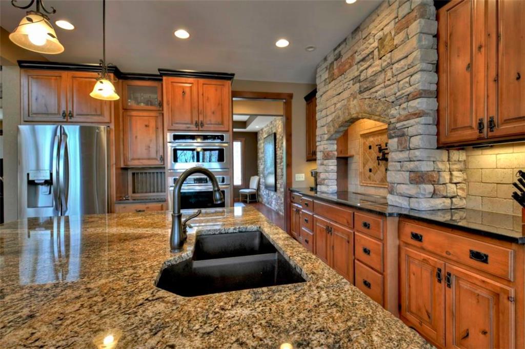 244 Wilderness Way Ellijay, GA 30536 - Photo 15 of 78 a kitchen with granite countertop a refrigerator a stove and a sink with wooden cabinets