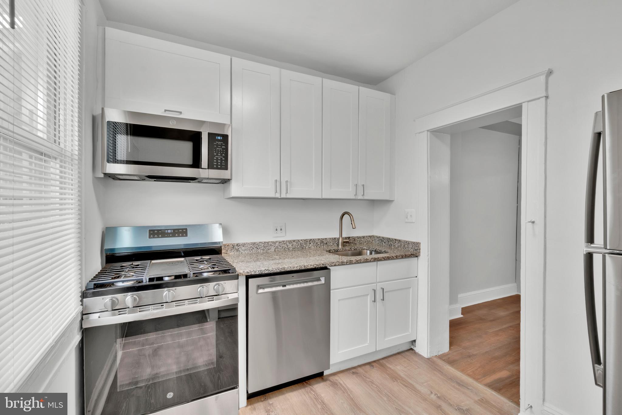 747 East 37th Street Baltimore, MD 21218 - Photo 18 of 53 a kitchen with stainless steel appliances granite countertop grey cabinets a stove a sink and a microwave