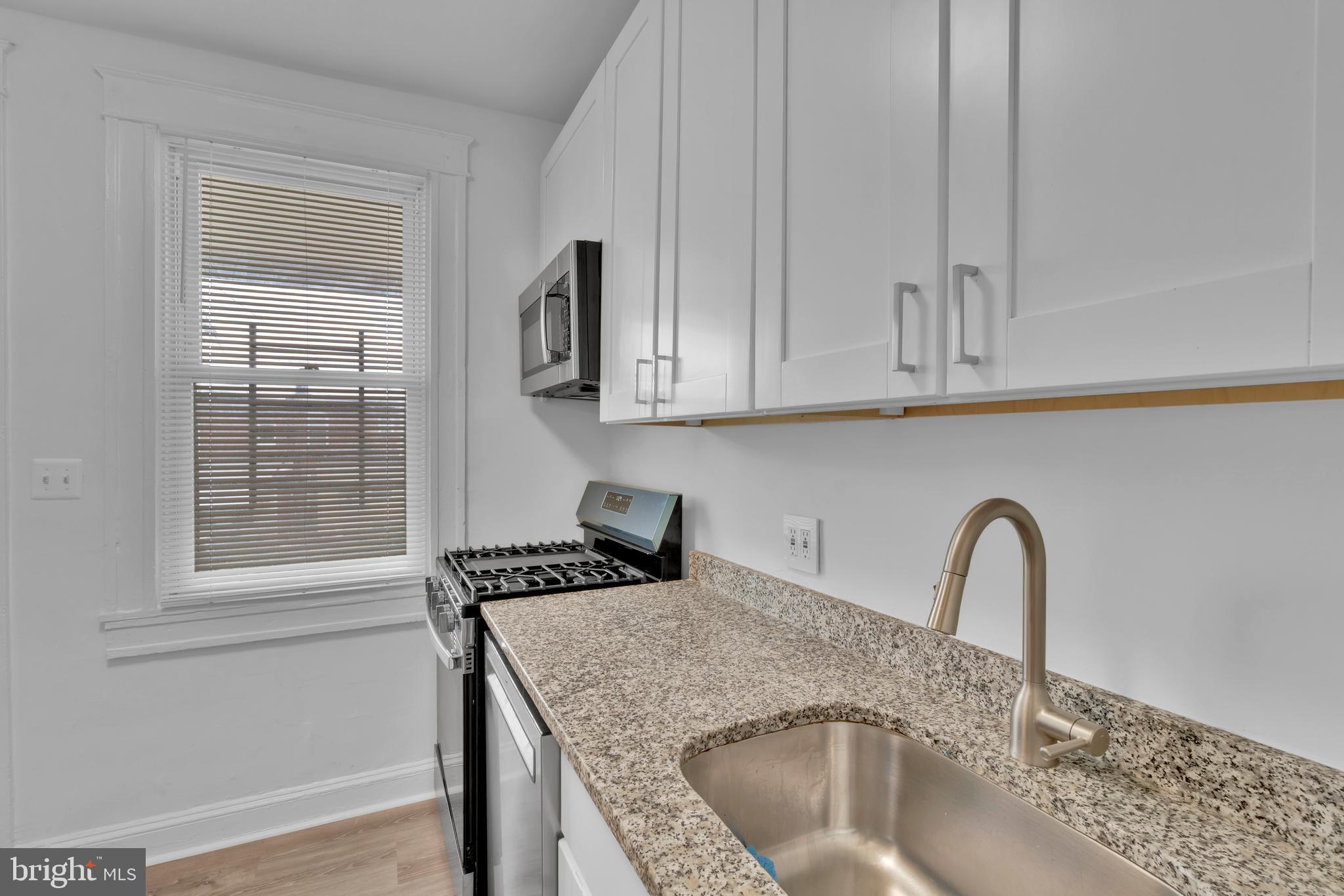 747 East 37th Street Baltimore, MD 21218 - Photo 20 of 53 a kitchen with granite countertop a sink and cabinets