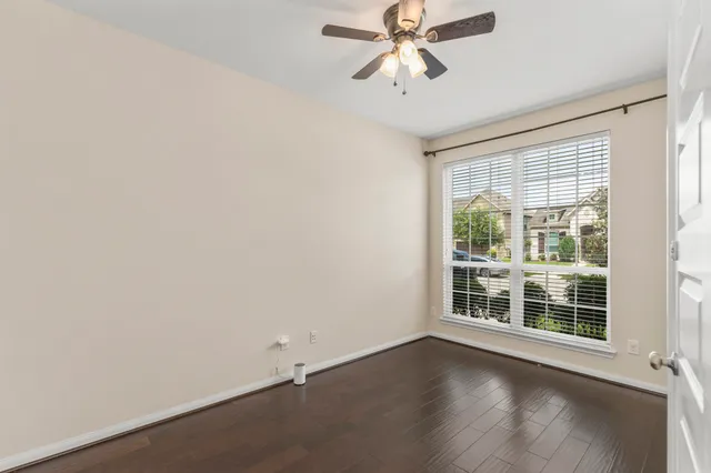 an empty room with wooden floor fan and windows