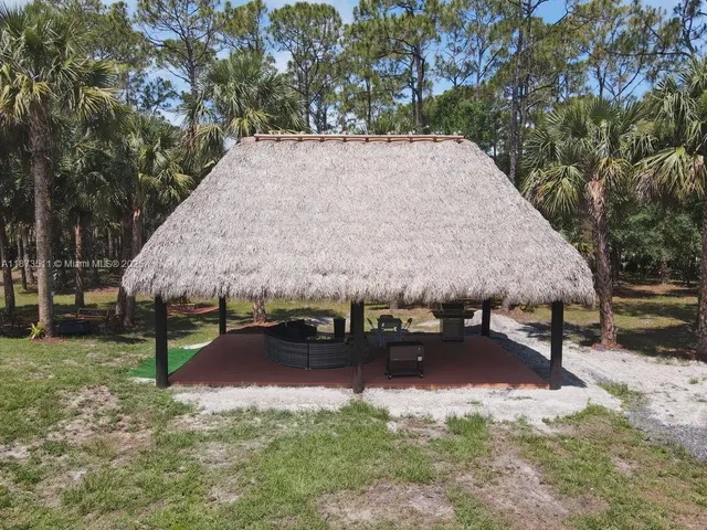 a view of patio with table and chairs under an umbrella with a small yard