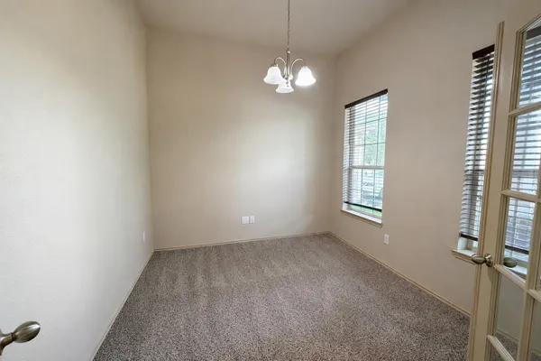 an empty room with chandelier fan and windows