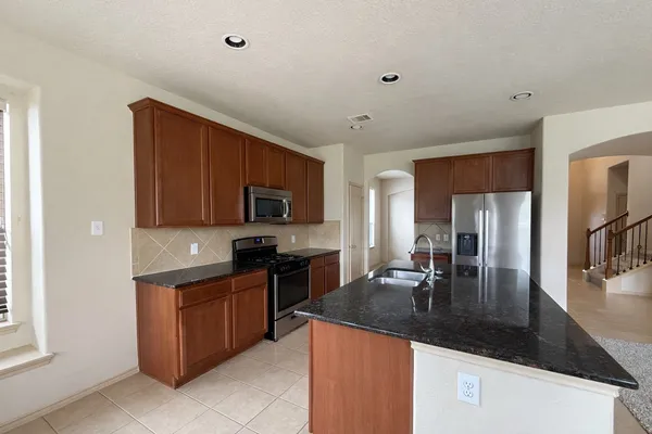 a kitchen with granite countertop a sink stainless steel appliances and cabinets
