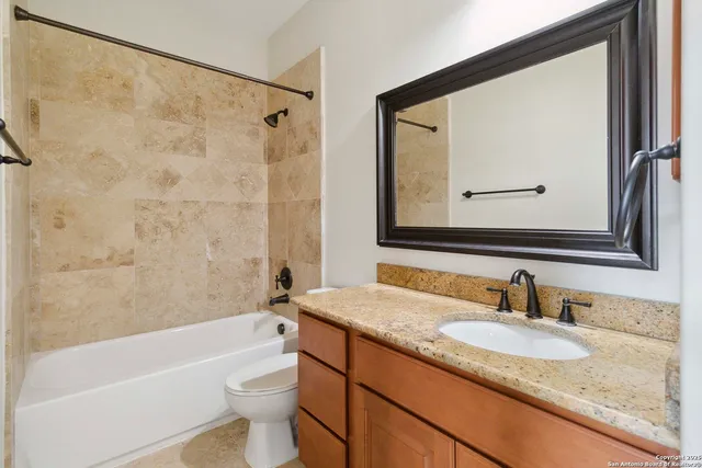a bathroom with a granite countertop sink a toilet and bathtub