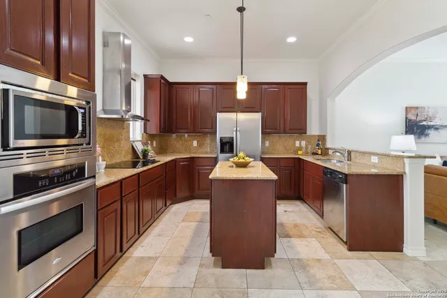 a kitchen with kitchen island granite countertop wooden cabinets and stainless steel appliances
