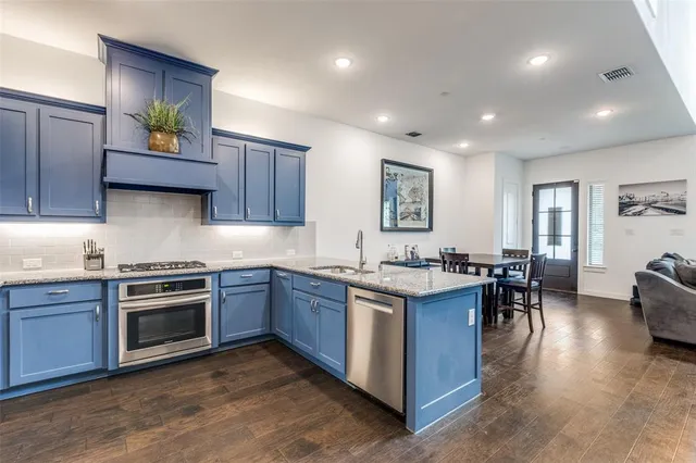 a kitchen with stainless steel appliances granite countertop wooden cabinets a stove a sink and a microwave