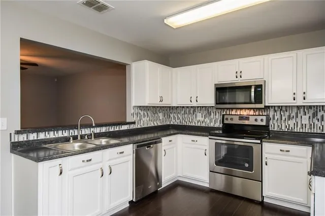 a kitchen with granite countertop white cabinets and white appliances
