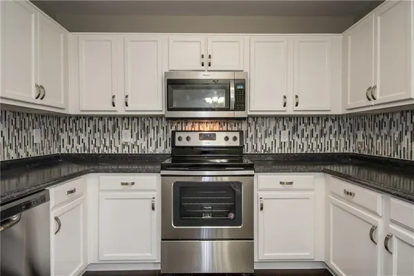 a kitchen with granite countertop white cabinets and white appliances