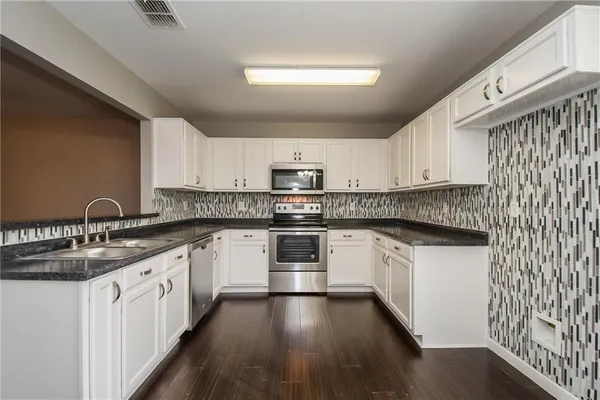 a kitchen with granite countertop white cabinets and white appliances