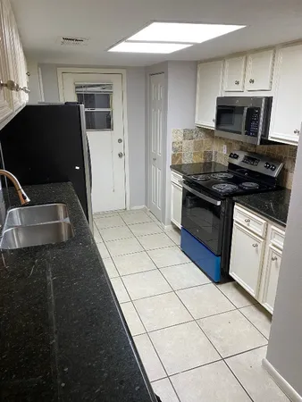 a kitchen with granite countertop a stove a sink and a microwave