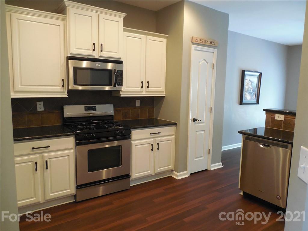 7015 Sedgewick Road Indian Trail, NC 28079 - Photo 11 of 14 a kitchen with granite countertop cabinets stainless steel appliances and wooden floor