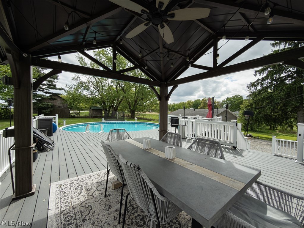 13429 West Calla Road Salem, OH 44460 - Photo 19 of 27 Spacious outdoor deck featuring a covered gazebo with a ceiling fan and string lighting, an above-ground swimming pool, and white railing