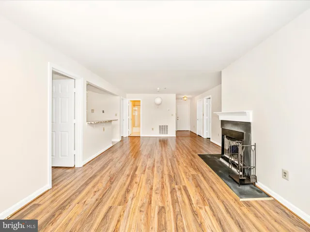a view of a livingroom with wooden floor and a fireplace