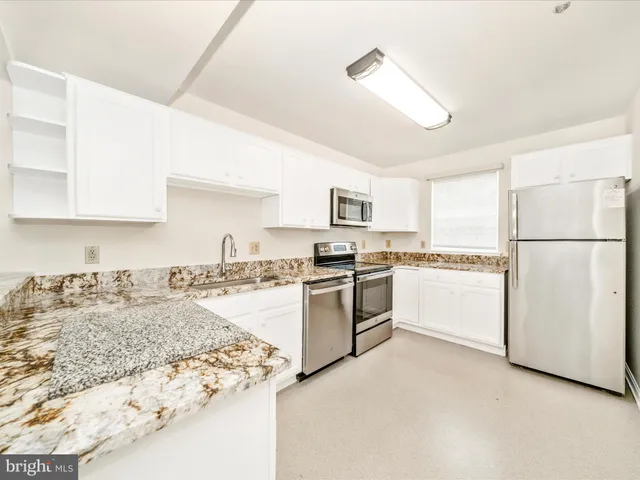 a kitchen with granite countertop white cabinets and white appliances