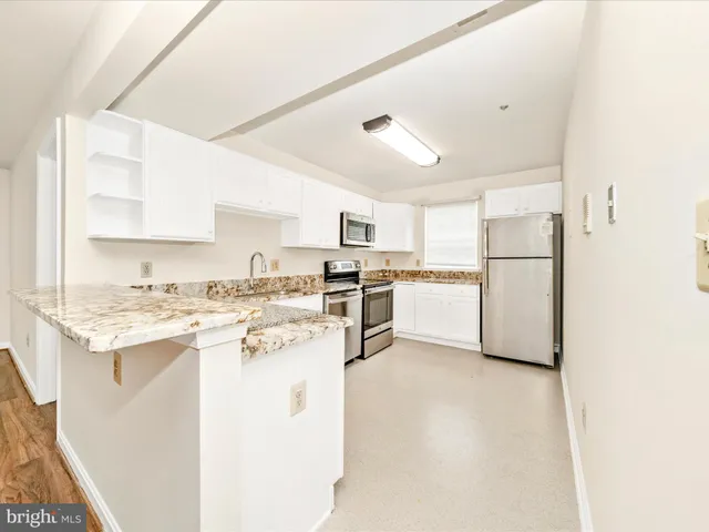 a kitchen with stainless steel appliances white cabinets and a refrigerator