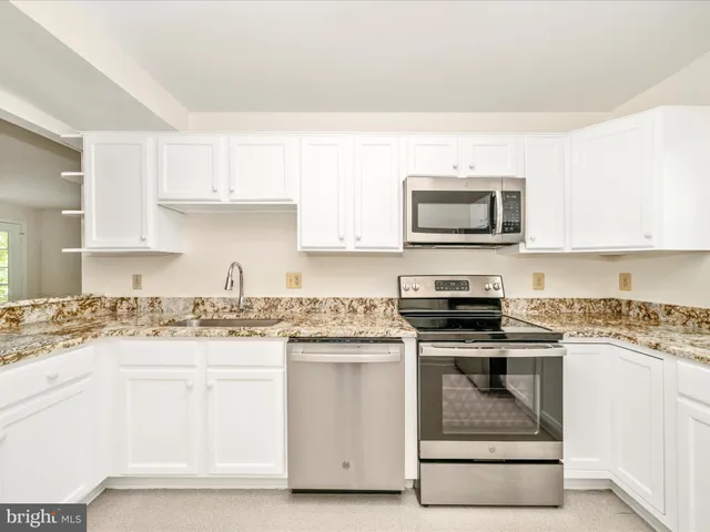 a kitchen with granite countertop a stove top oven microwave and cabinets