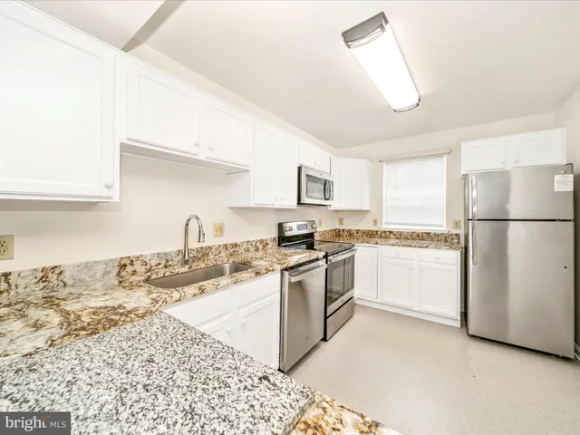 a kitchen with granite countertop white cabinets and white appliances