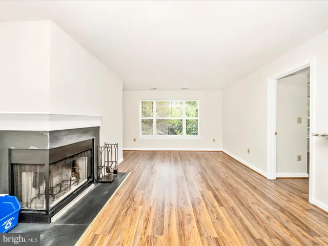 an empty room with wooden floor fireplace and windows