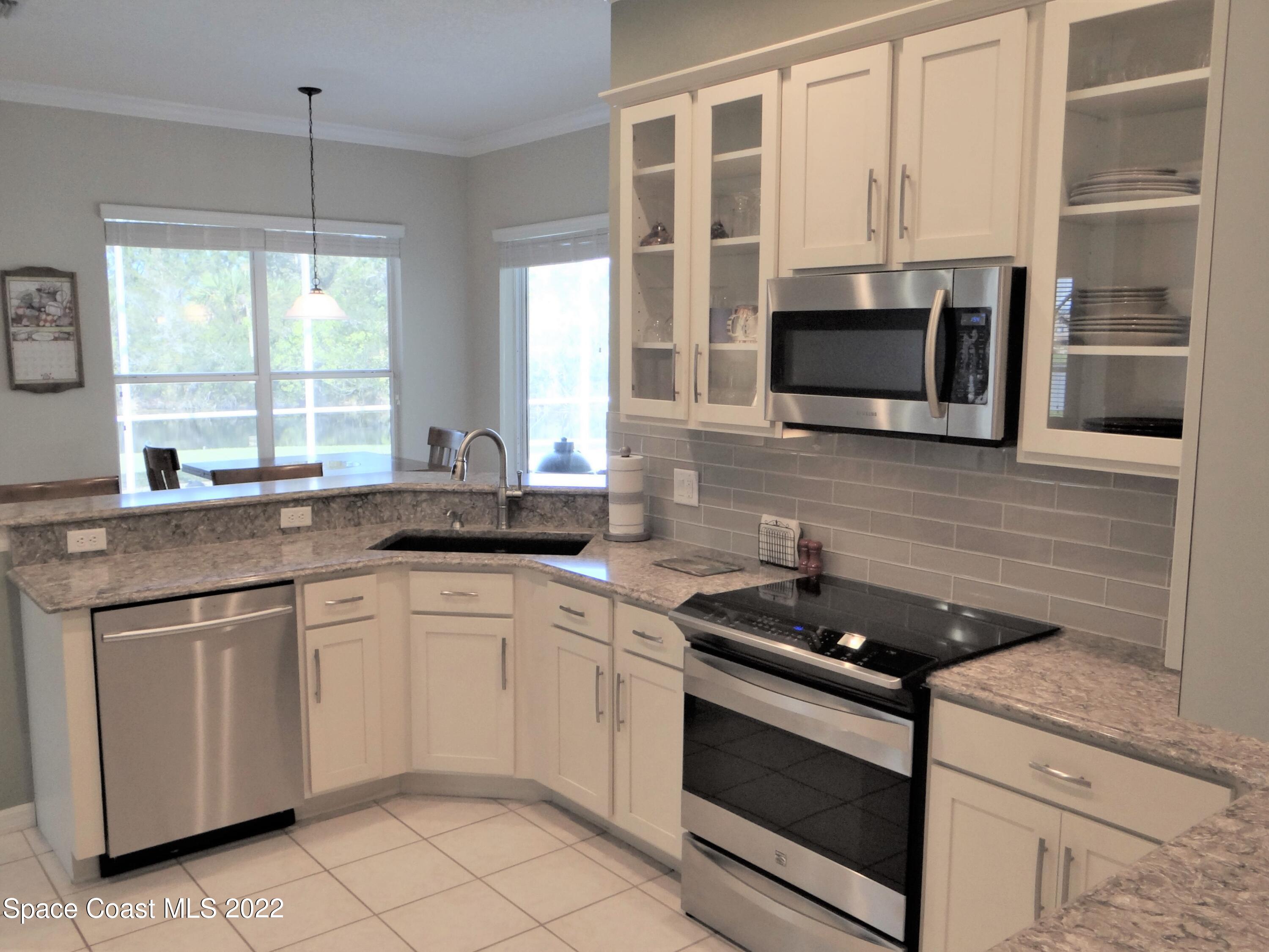 3100 Huntleigh Way Melbourne, FL 32934 - Photo 12 of 54 a kitchen with stainless steel appliances a stove sink and microwave