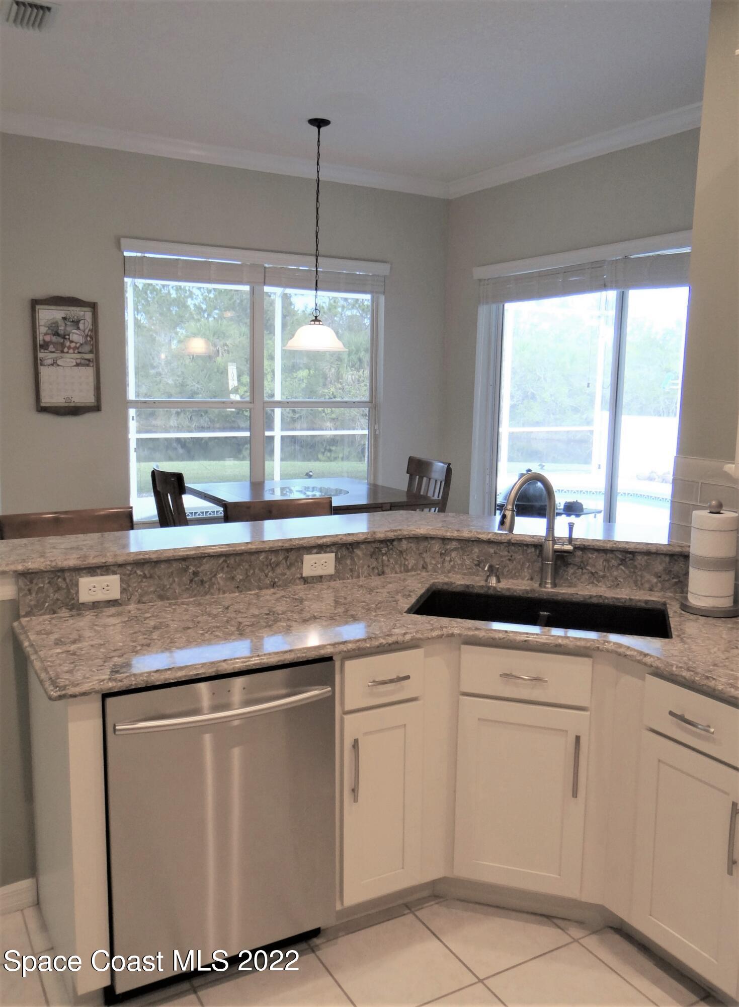 3100 Huntleigh Way Melbourne, FL 32934 - Photo 13 of 54 a kitchen with granite countertop white cabinets and a large window