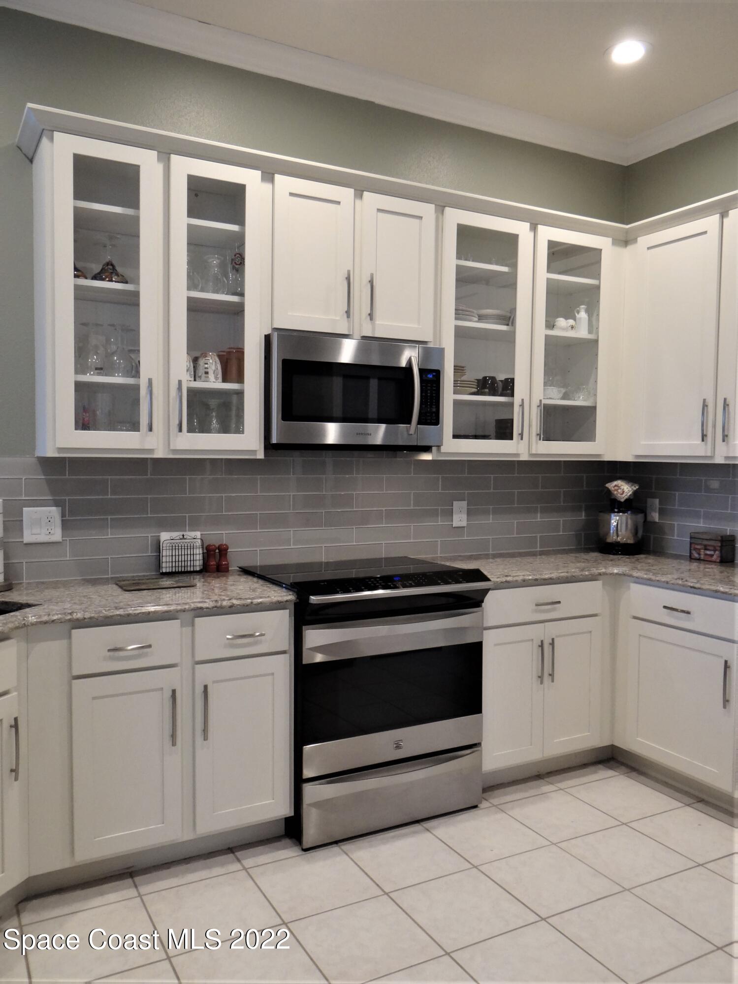 3100 Huntleigh Way Melbourne, FL 32934 - Photo 14 of 54 a kitchen with stainless steel appliances granite countertop a stove a sink and a microwave