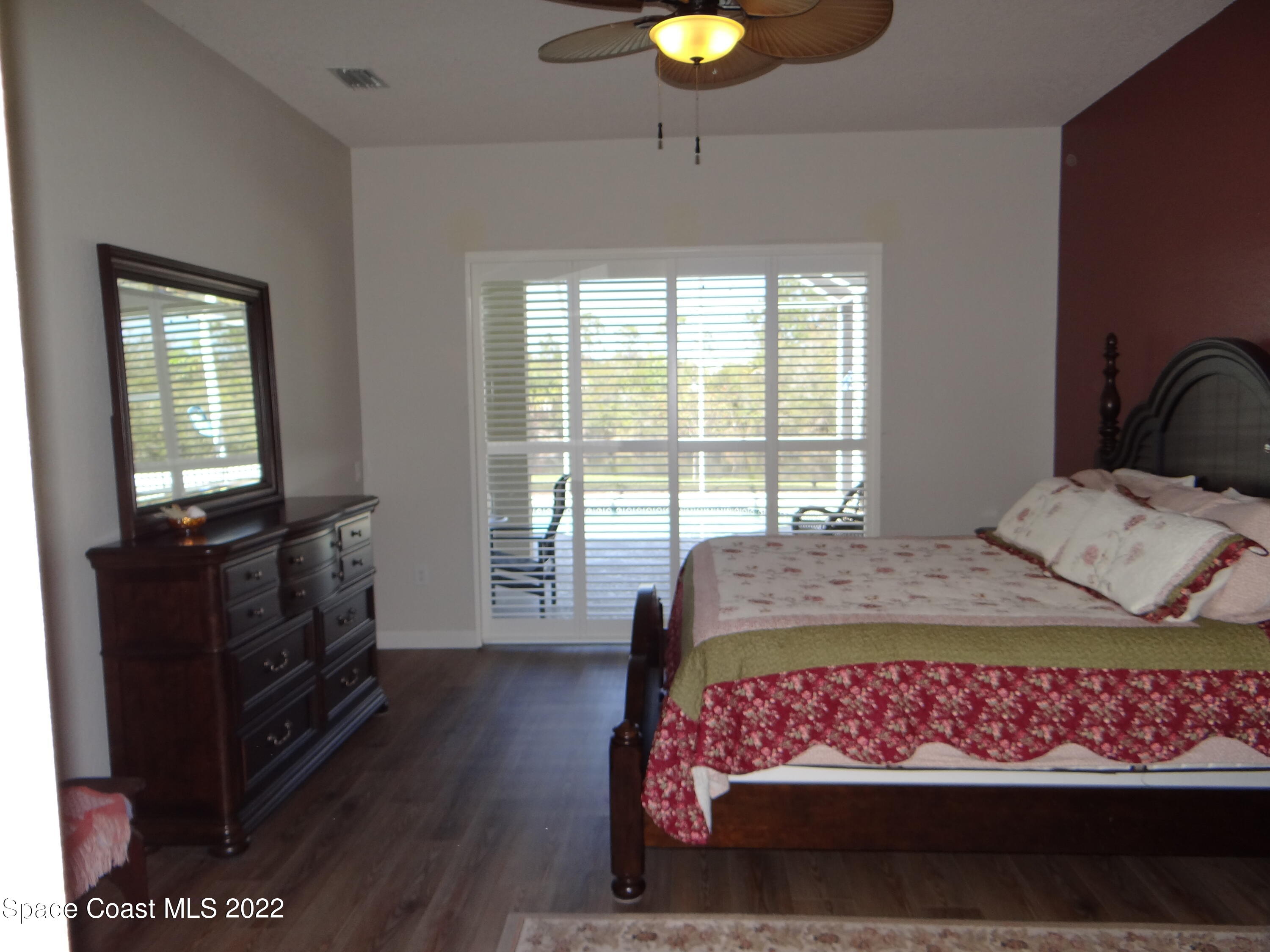3100 Huntleigh Way Melbourne, FL 32934 - Photo 21 of 54 a bedroom with a bed and wooden floor