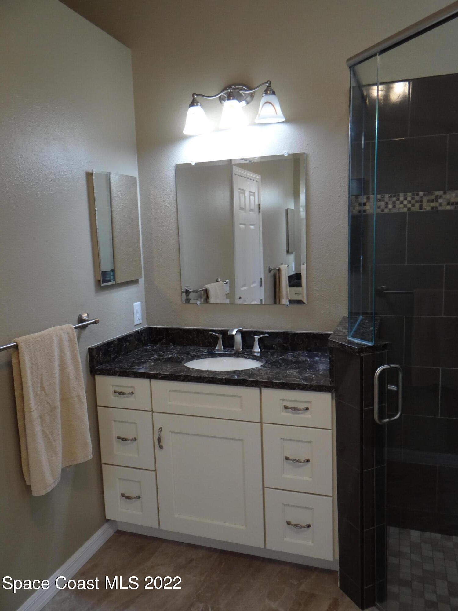 3100 Huntleigh Way Melbourne, FL 32934 - Photo 28 of 54 a bathroom with a granite countertop sink a mirror and a vanity