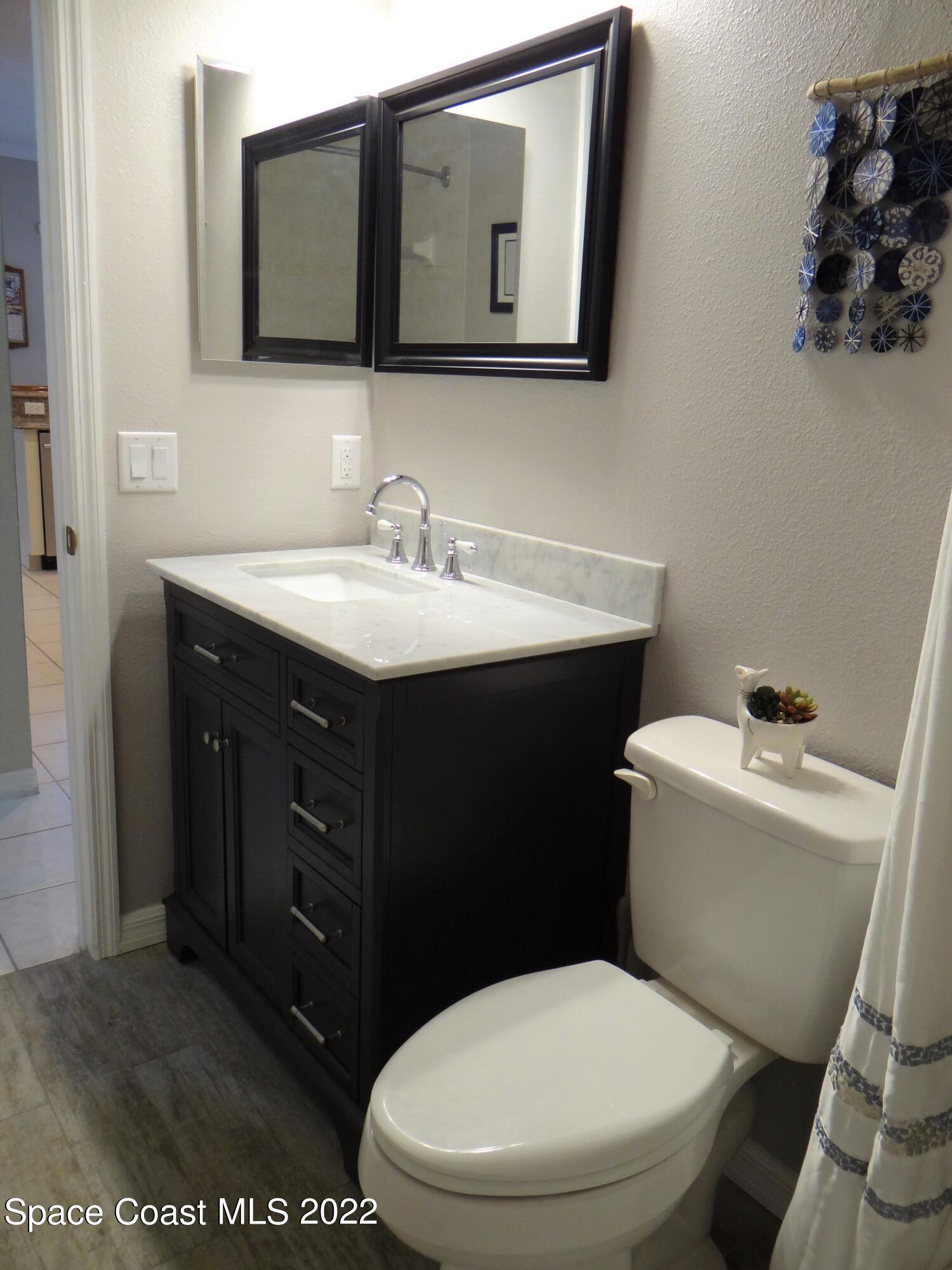 3100 Huntleigh Way Melbourne, FL 32934 - Photo 35 of 54 a bathroom with a toilet a sink and mirror