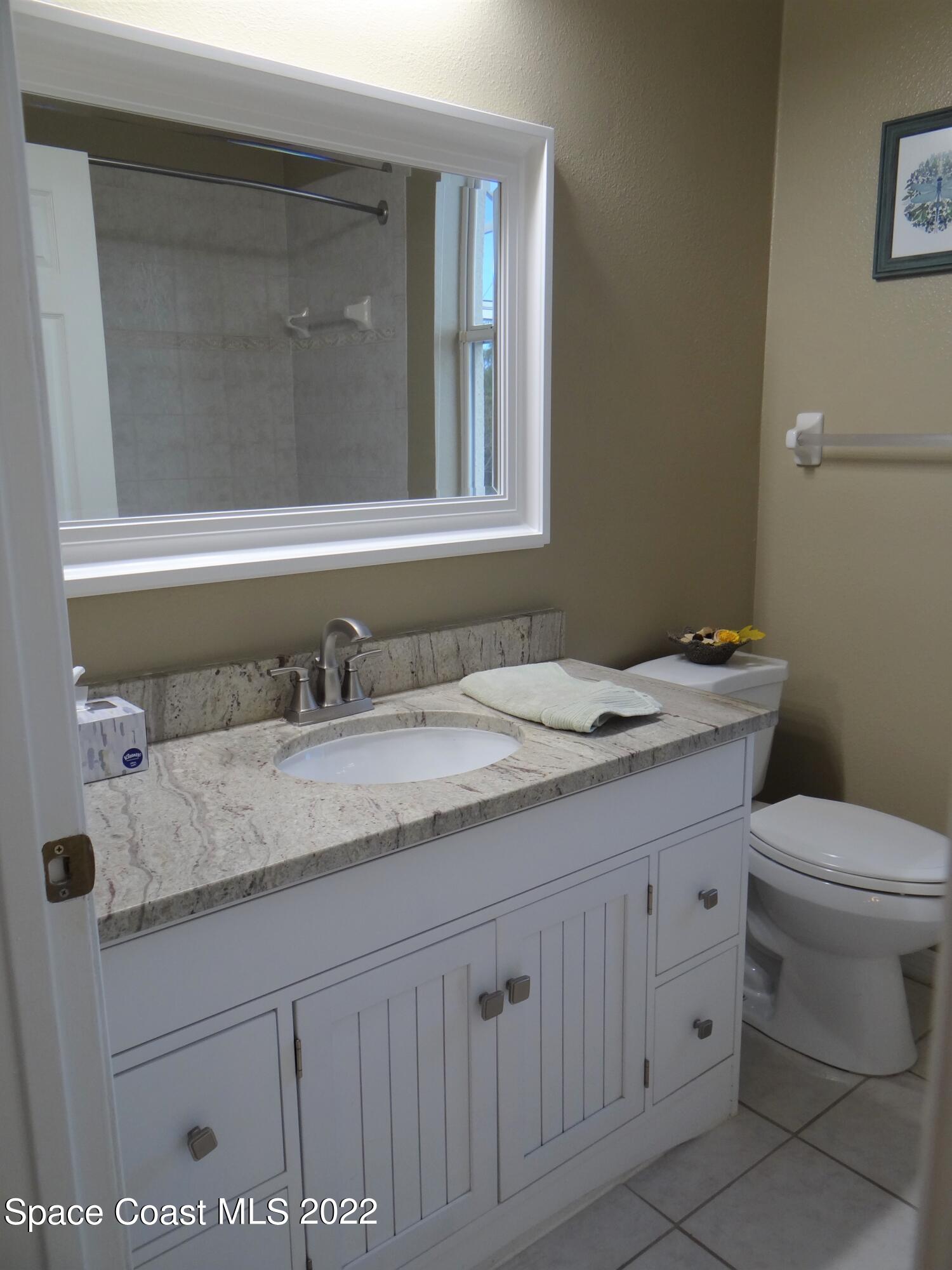 3100 Huntleigh Way Melbourne, FL 32934 - Photo 38 of 54 a bathroom with a granite countertop sink a toilet and a mirror