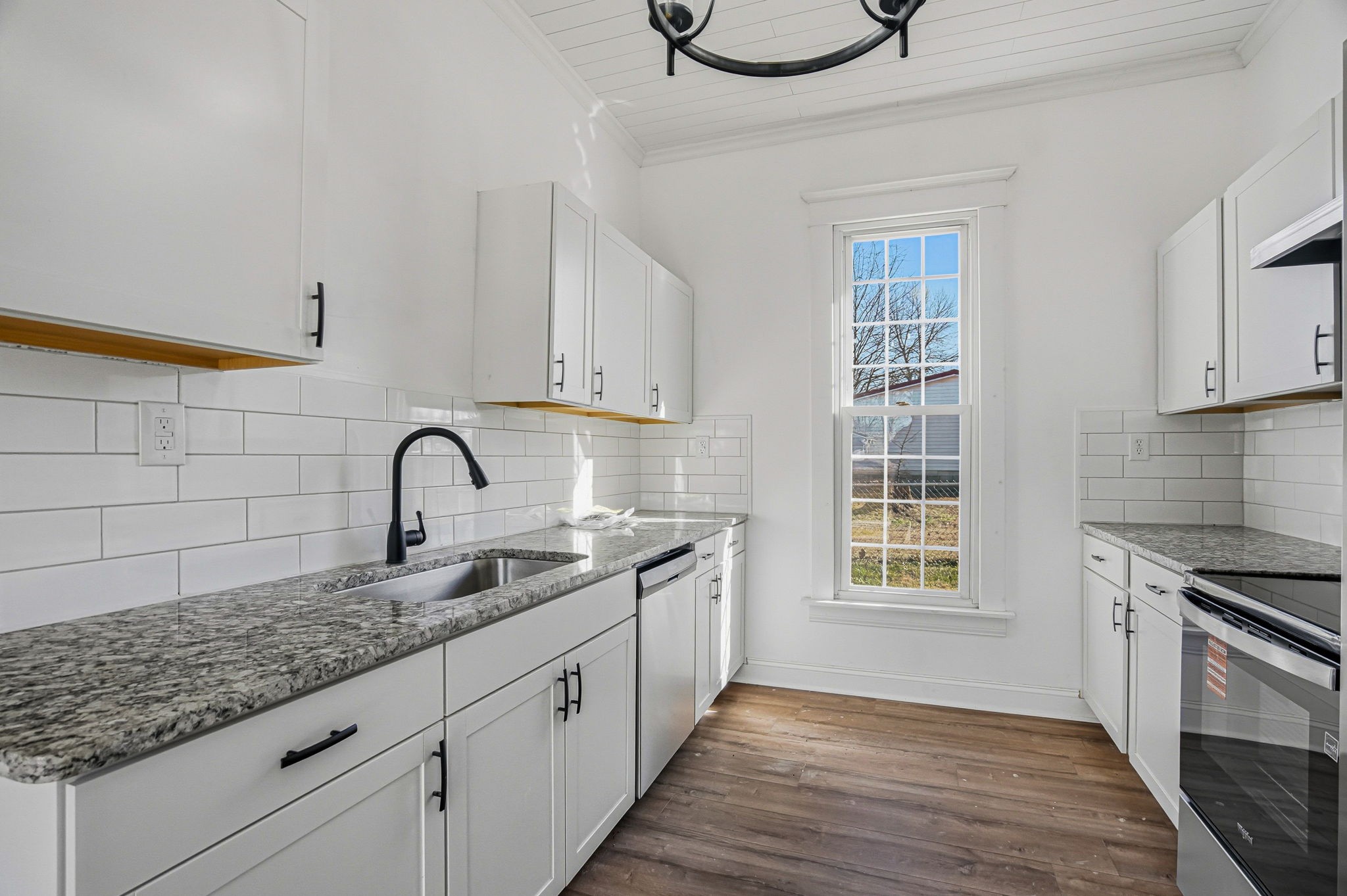204 Winters Street Adams, TN 37010 - Photo 14 of 18 a kitchen with granite countertop a sink stainless steel appliances wooden floor and cabinets