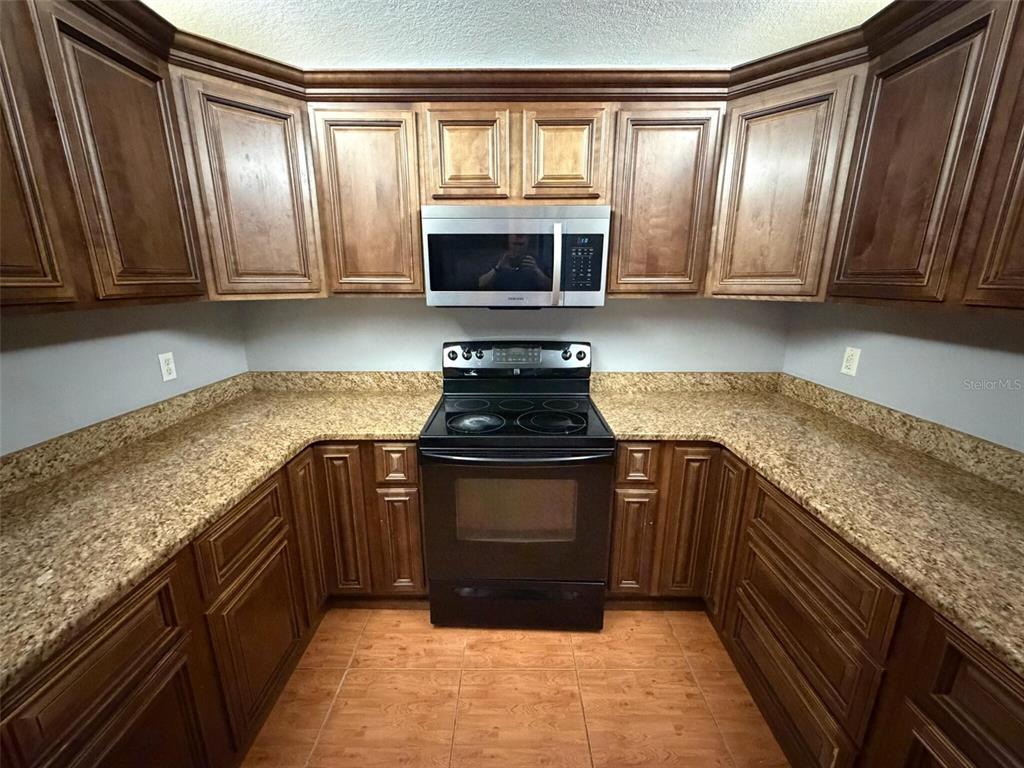 9816 East Granada Court Inverness, FL 34450 - Photo 17 of 28 a kitchen with granite countertop a stove a sink and a microwave