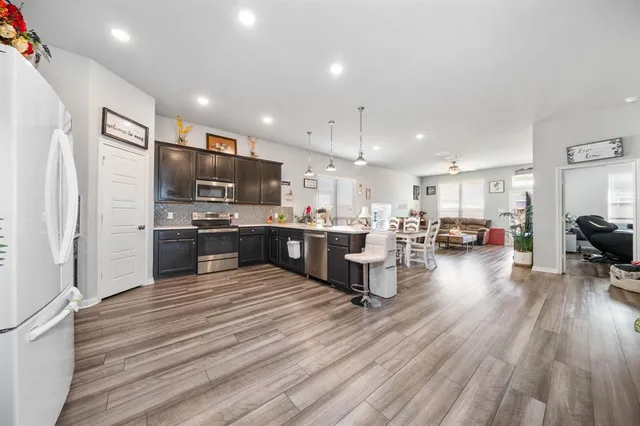 a kitchen with stainless steel appliances a refrigerator and a wooden floor