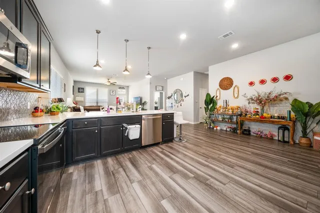 a kitchen with stainless steel appliances granite countertop a stove a sink dishwasher and a refrigerator with wooden floor