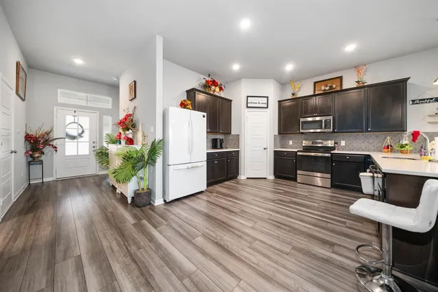 a kitchen with stainless steel appliances kitchen island granite countertop a refrigerator oven a sink dishwasher and a stove with wooden floor