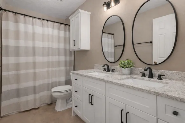 a bathroom with a granite countertop toilet a sink and a mirror