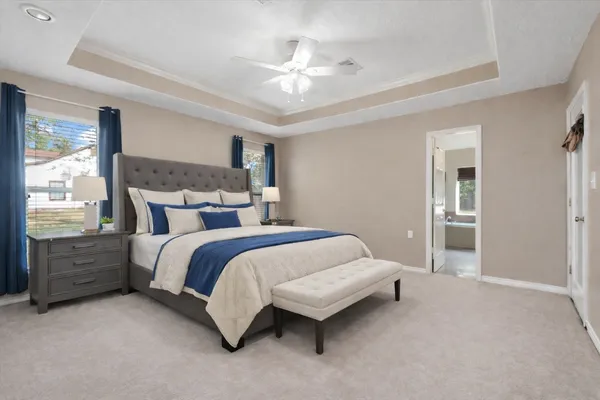 a bedroom with a large bed and a chandelier fan