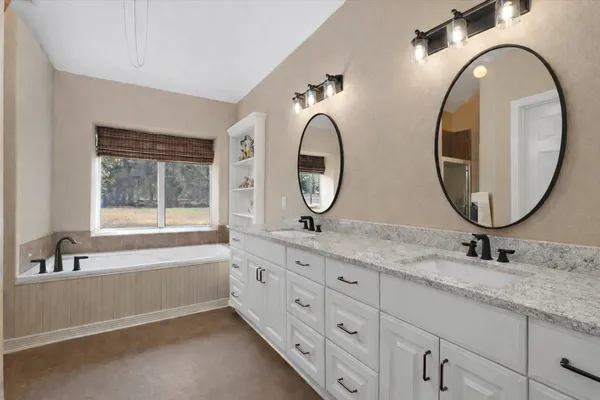 a bathroom with a granite countertop double vanity sink and a mirror