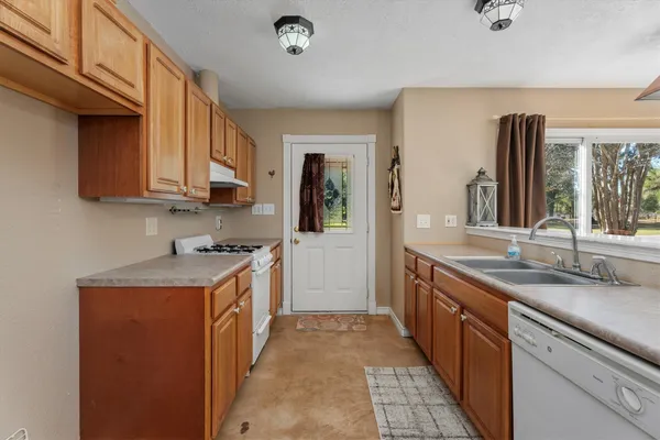 a kitchen with granite countertop a sink stove and cabinets