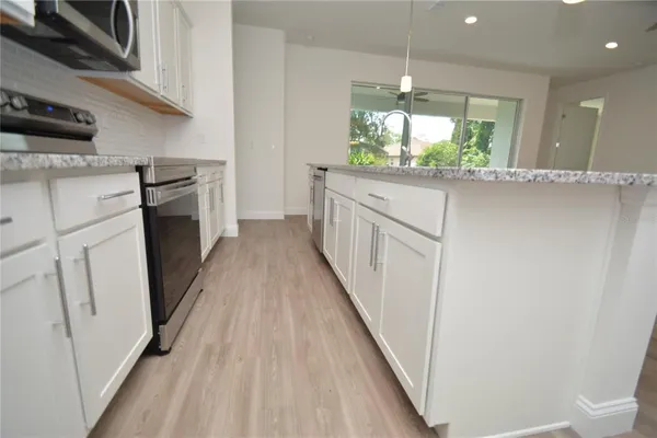 a kitchen with white cabinets and window