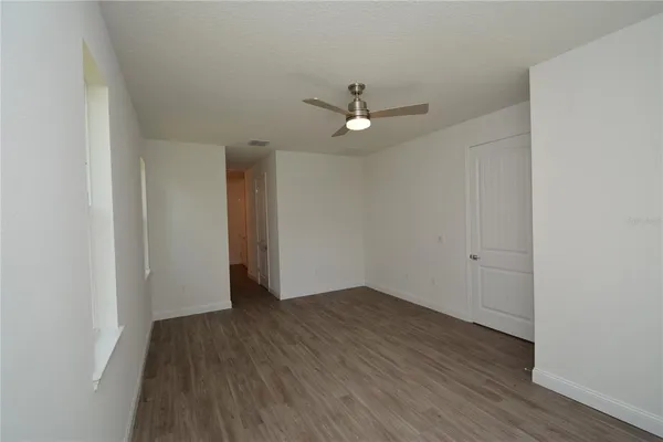 an empty room with wooden floor and ceiling fan