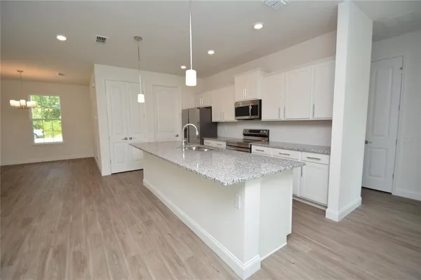 a large kitchen with stainless steel appliances granite countertop a sink a stove a microwave a center island and cabinets