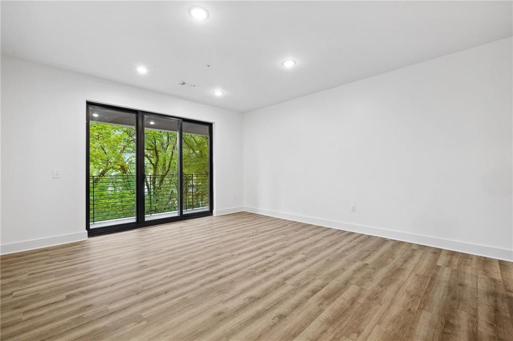 112 Rogers Street Northeast, Unit 304 Atlanta, GA 30317 - Photo 7 of 22 a view of an empty room with wooden floor and a window
