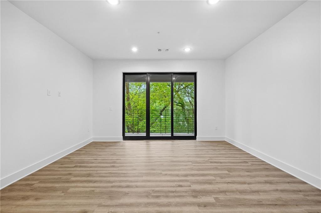 112 Rogers Street Northeast, Unit 304 Atlanta, GA 30317 - Photo 8 of 22 a view of an empty room with wooden floor and a window